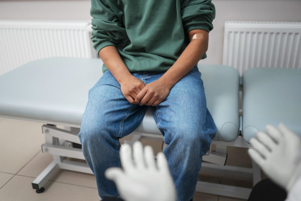 Doente sentado na maca de consultório durante avaliação urológica, representando o acompanhamento clínico no tratamento da disfunção erétil