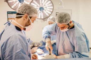 Cirurgião e equipe médica realizando enxerto peniano cirúrgico procedimento em sala de operação, com uso de máscaras, luvas e iluminação cirúrgica em ambiente hospitalar estéril