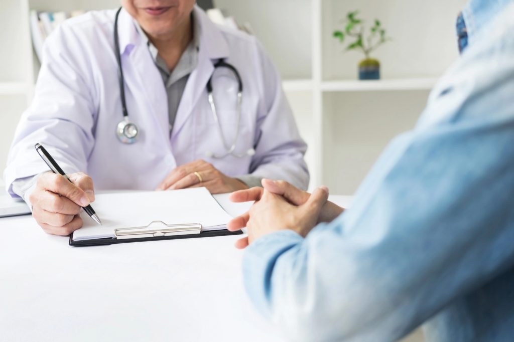 Médico urologista a atender paciente homem e orientando sobre segunda cirurgia de peyronie