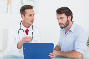Doente e urologista em ambiente clínico, a avaliar exames num tablet e a discutir o tratamento com ondas de choque Doença de Peyronie