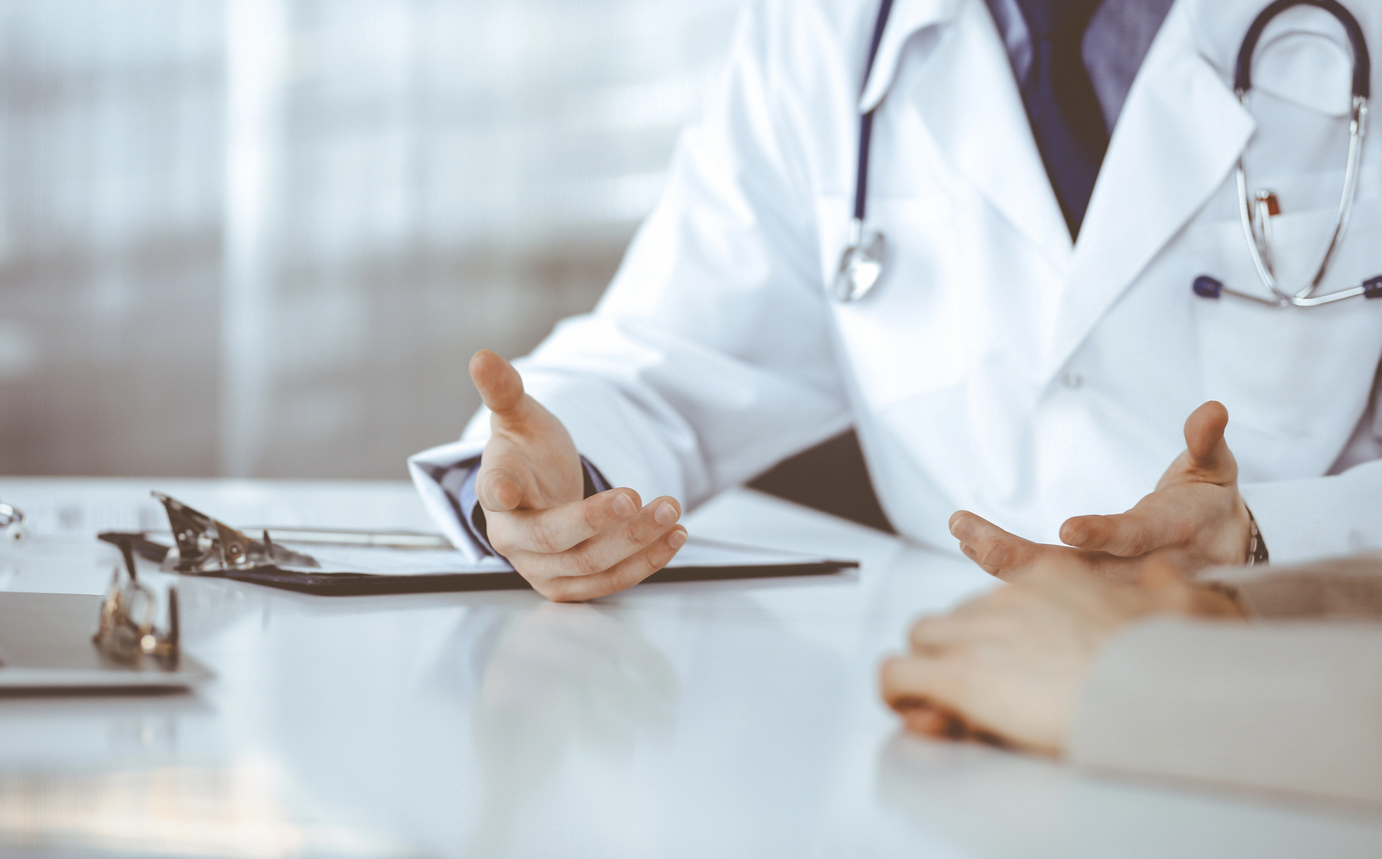 Médico urologista a analisar exames clínicos junto ao doente, em ambiente de consultório médico em Portugal.