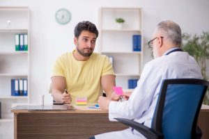 Especialista em urologia indica terapia por ondas de choque de baixa intensidade num doente com Doença de Peyronie, em ambiente clínico.
