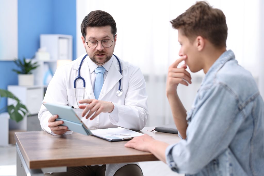 Médico urologista explica a um doente, durante uma consulta, como a cirurgia da Doença de Peyronie pode influenciar a função sexual e a qualidade de vida após a recuperação.