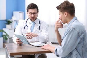 Médico urologista explica a um doente, durante uma consulta, como a cirurgia da Doença de Peyronie pode influenciar a função sexual e a qualidade de vida após a recuperação.