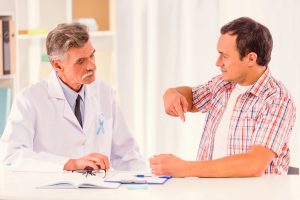 Médico urologista explica a um doente os fatores que podem influenciar a recidiva da Doença de Peyronie após a cirurgia .